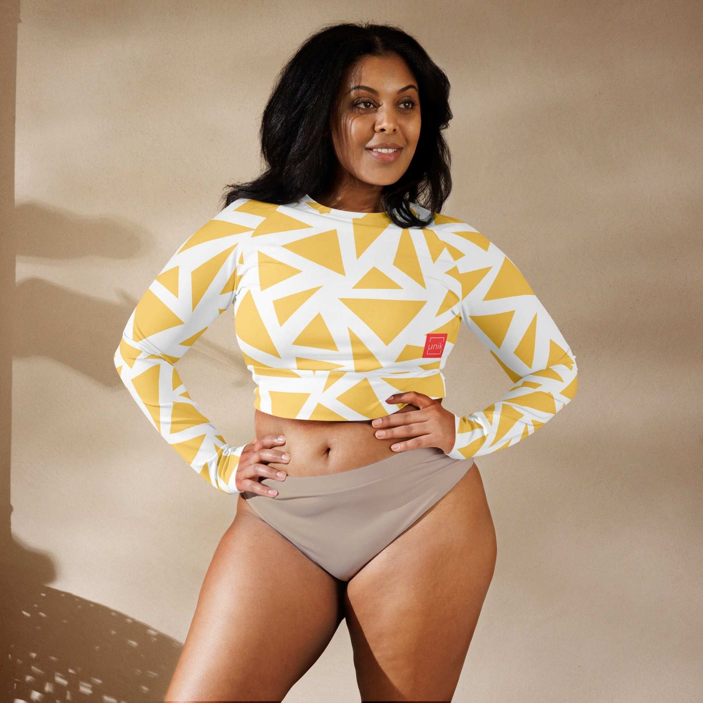 Model wearing unik.fashion eco-friendly geometric print crop top with long sleeves and beige bottoms