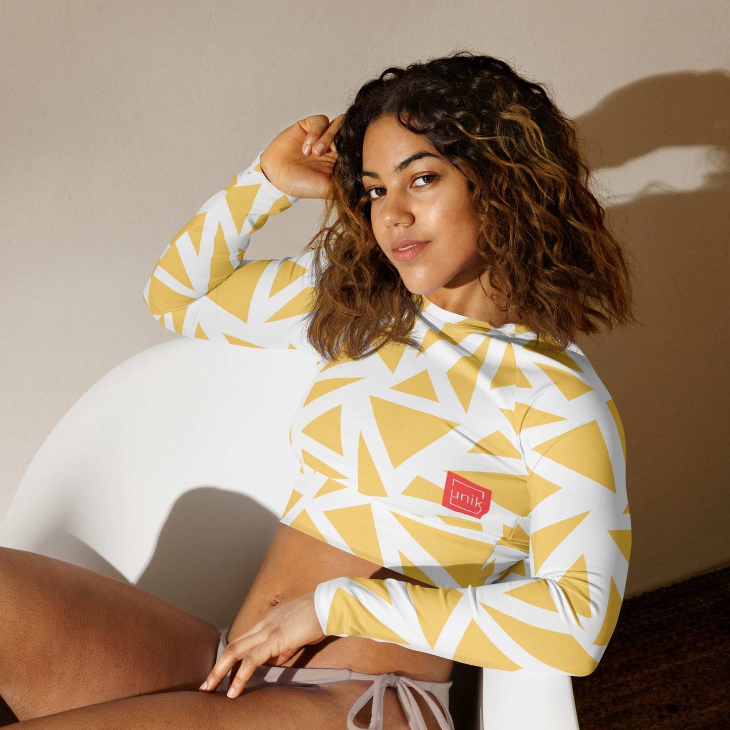 Eco-friendly geometric print crop top in yellow and white worn by woman sitting on white chair