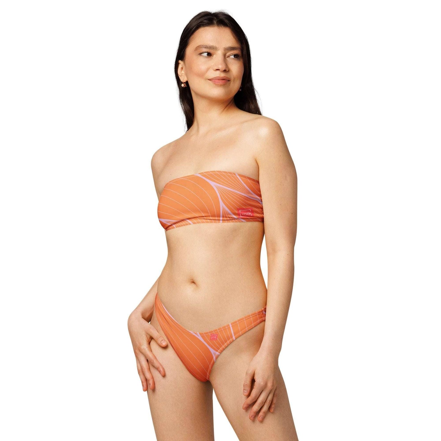 Woman wearing an orange sustainable bandeau bikini with white abstract lines by unik.fashion
